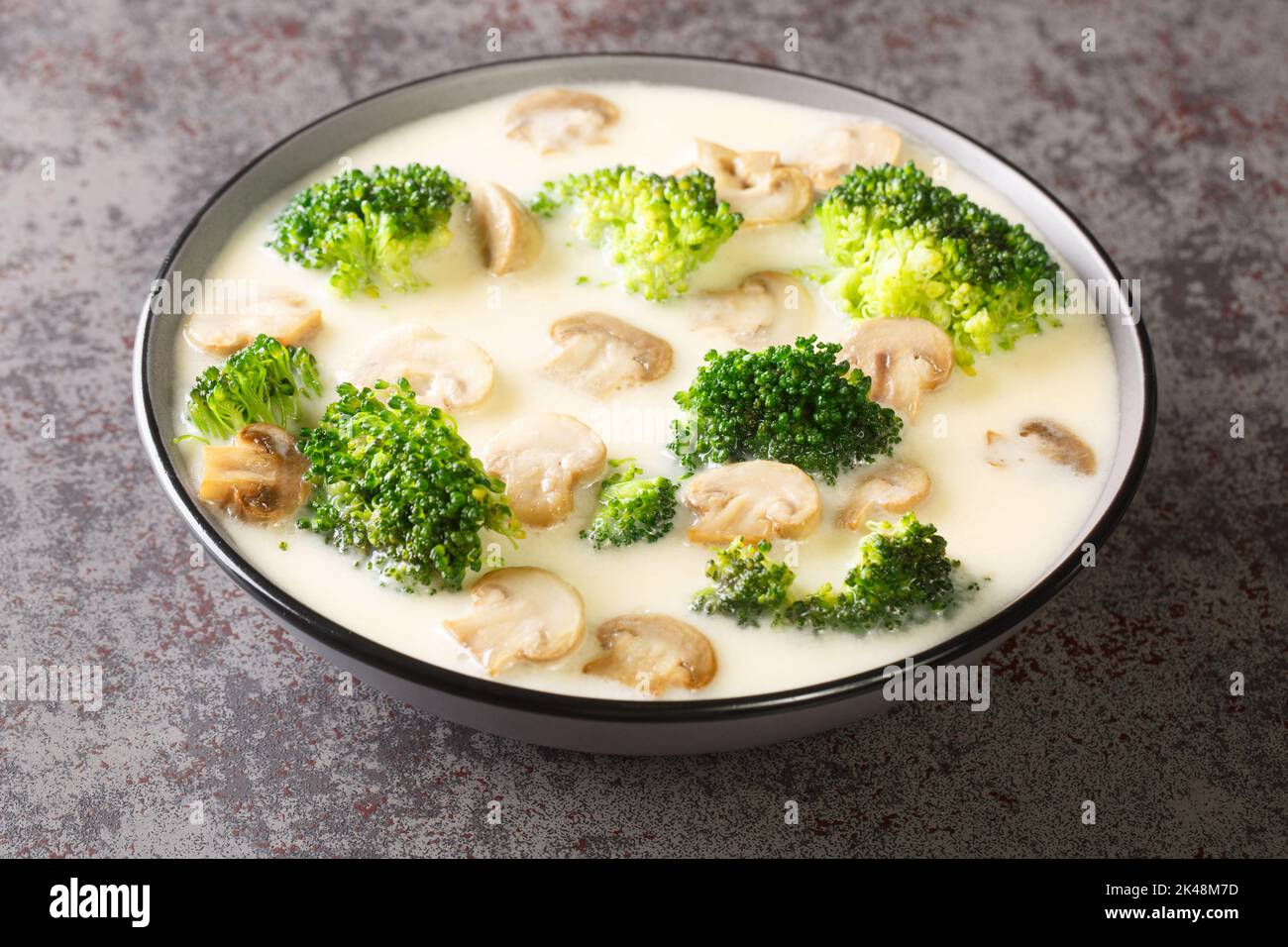 Thick fragrant cream soup with broccoli and champignon mushrooms close-up in a bowl on the table. Horizontal Stock Photo