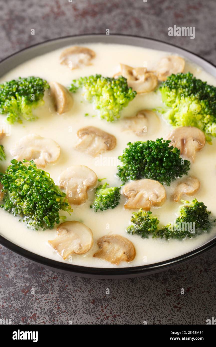 Bowl with delicious mushroom soup with cream and broccoli close-up on the table. Vertical Stock Photo