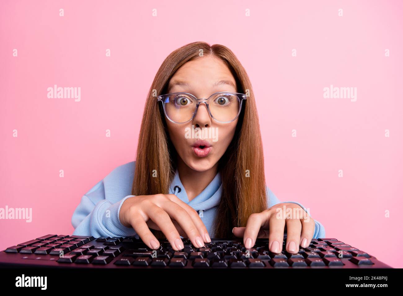 Portrait of crazy impressed person typing keyboard pouted lips staring isolated on pink color background Stock Photo