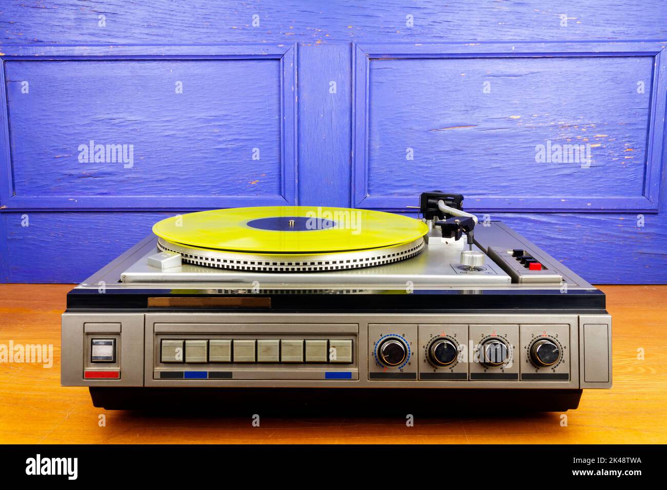 Vintage turntable vinyl record player with yellow vinyl on a table ...