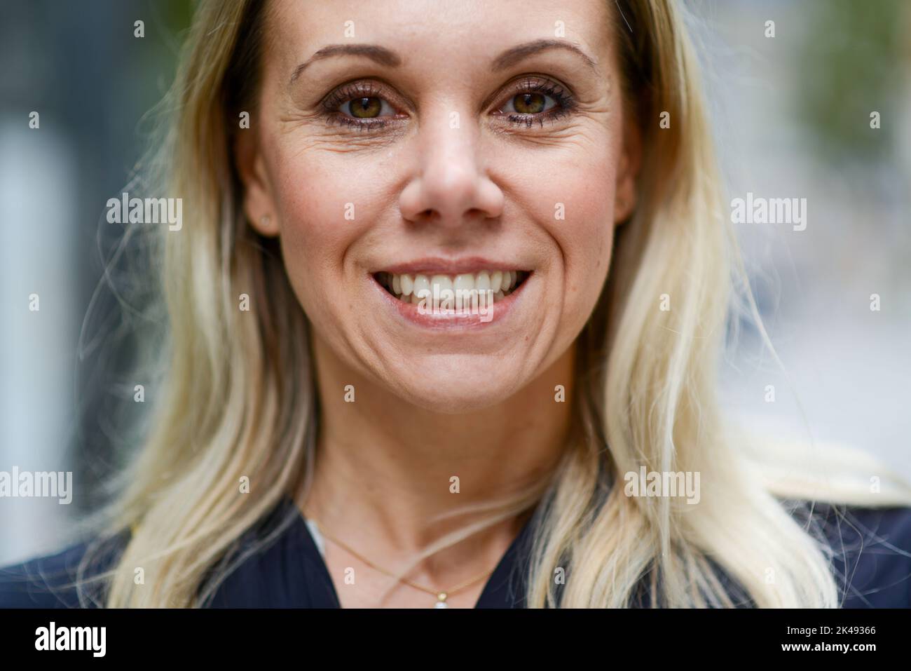 Close up of an attractive middle aged blond woman with an extremely wide and bright smile showing her teeth Stock Photo