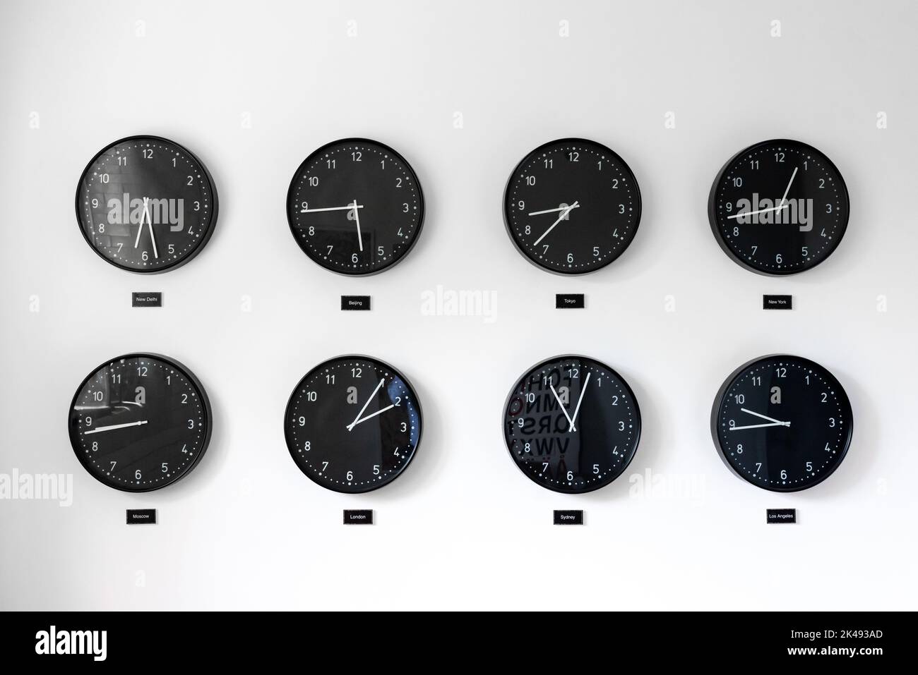 Different times al around the world including Great Britain, Russia and Honk Kong. Eight clocks on wall showing world time zones. Stock Photo