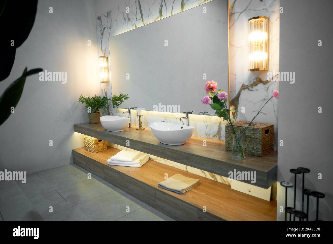 Bathroom with large mirror, two sinks and flowers. Stock Photo