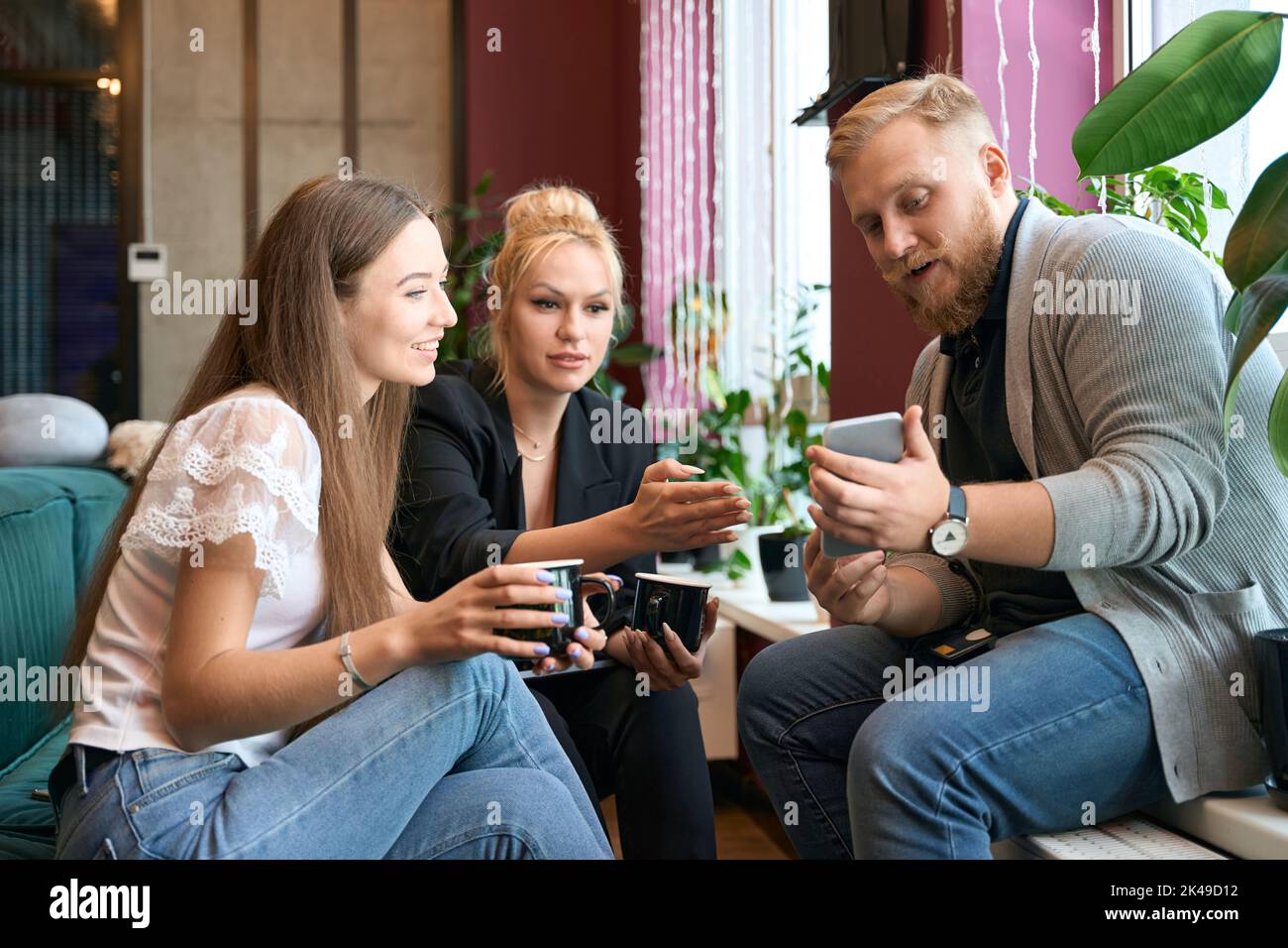Young man demonstrating photos on his mobile phone to colleagues Stock ...