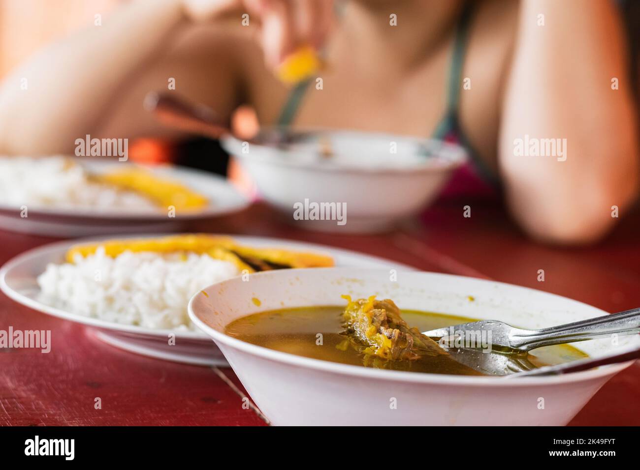 detailed view of a table served with a typical colombian breakfast, made with beef broth, in the background three white plates with rice and yellow ar Stock Photo