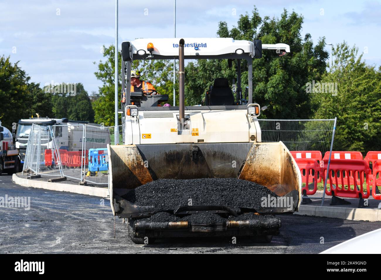 asphalt paver laying tarmac on a new road Stock Photo