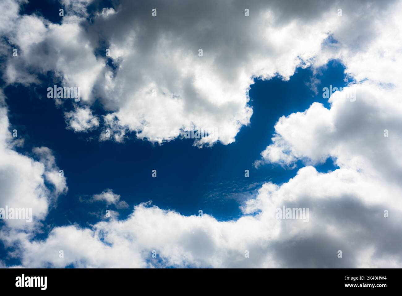 Blue sky and fluffy clouds illuminated by the day sun light. Nature background Stock Photo