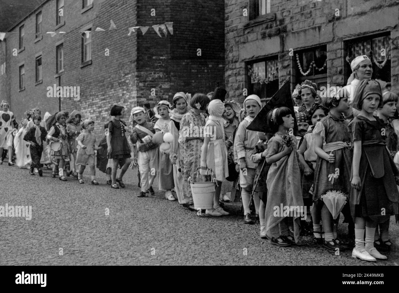 Excited youngsters in homemade fancy dress laugh and chatter as they wait, probably in Wakefield Road, to walk on in the procession held on 6 May 1935 to celebrate the Silver Jubilee of King George V at Denby Dale in West Yorkshire, England, UK. Stock Photo