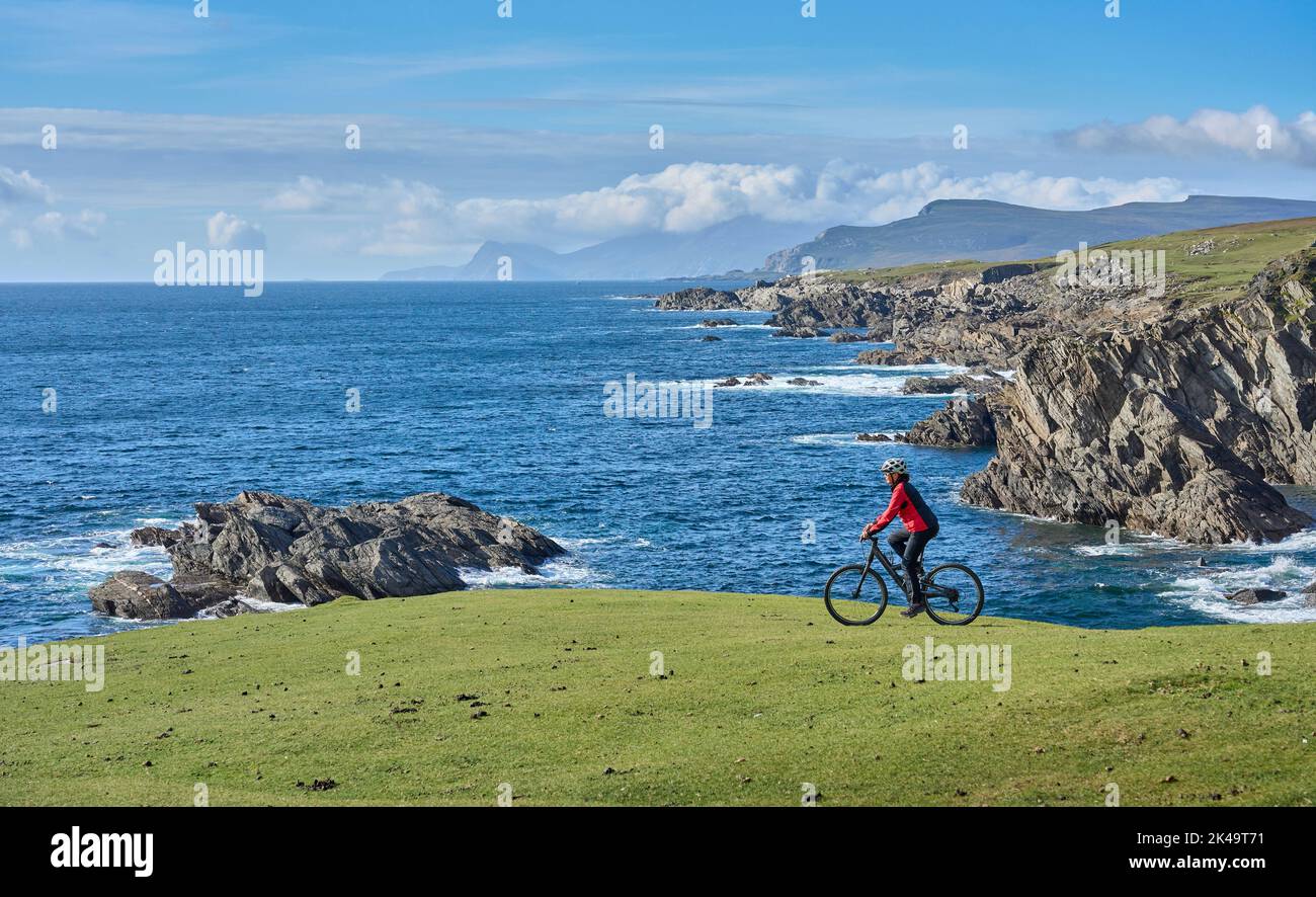 nice senior woman on mountain bike, cycling on the cliffs of Achill Island, Carrowgarve, Republik of Ireland Stock Photo