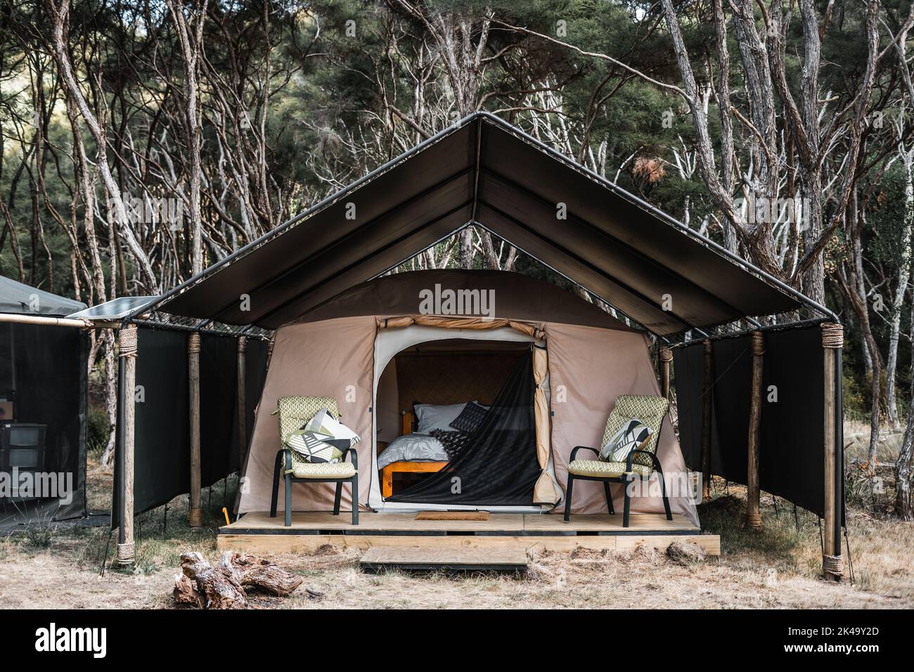 camping tent with mattress bed and cushions with terrace and chairs in