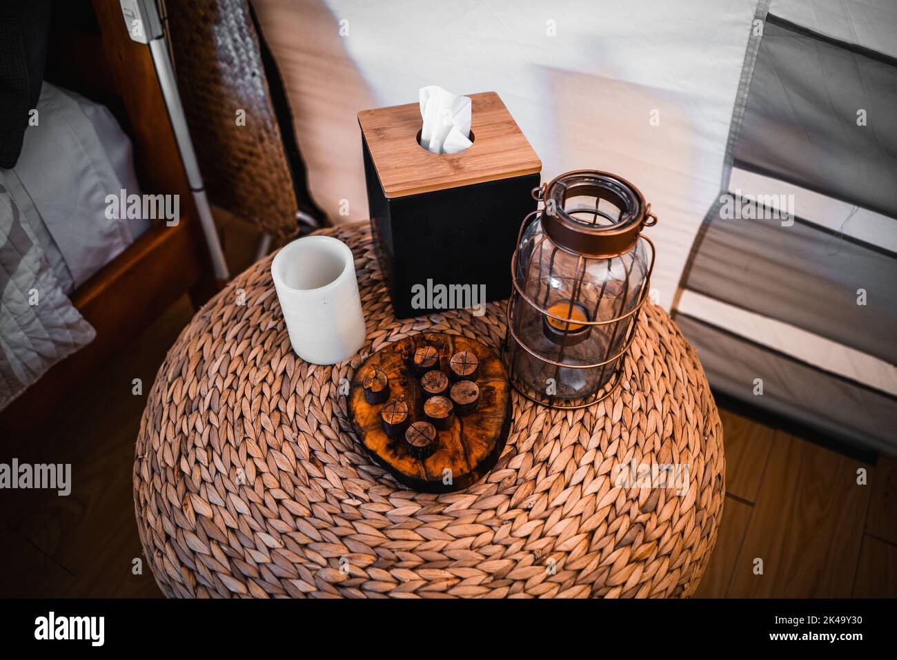 white round candle wooden tissue box cut tree trunk and glass lamp on rattan round nightstand in store Stock Photo