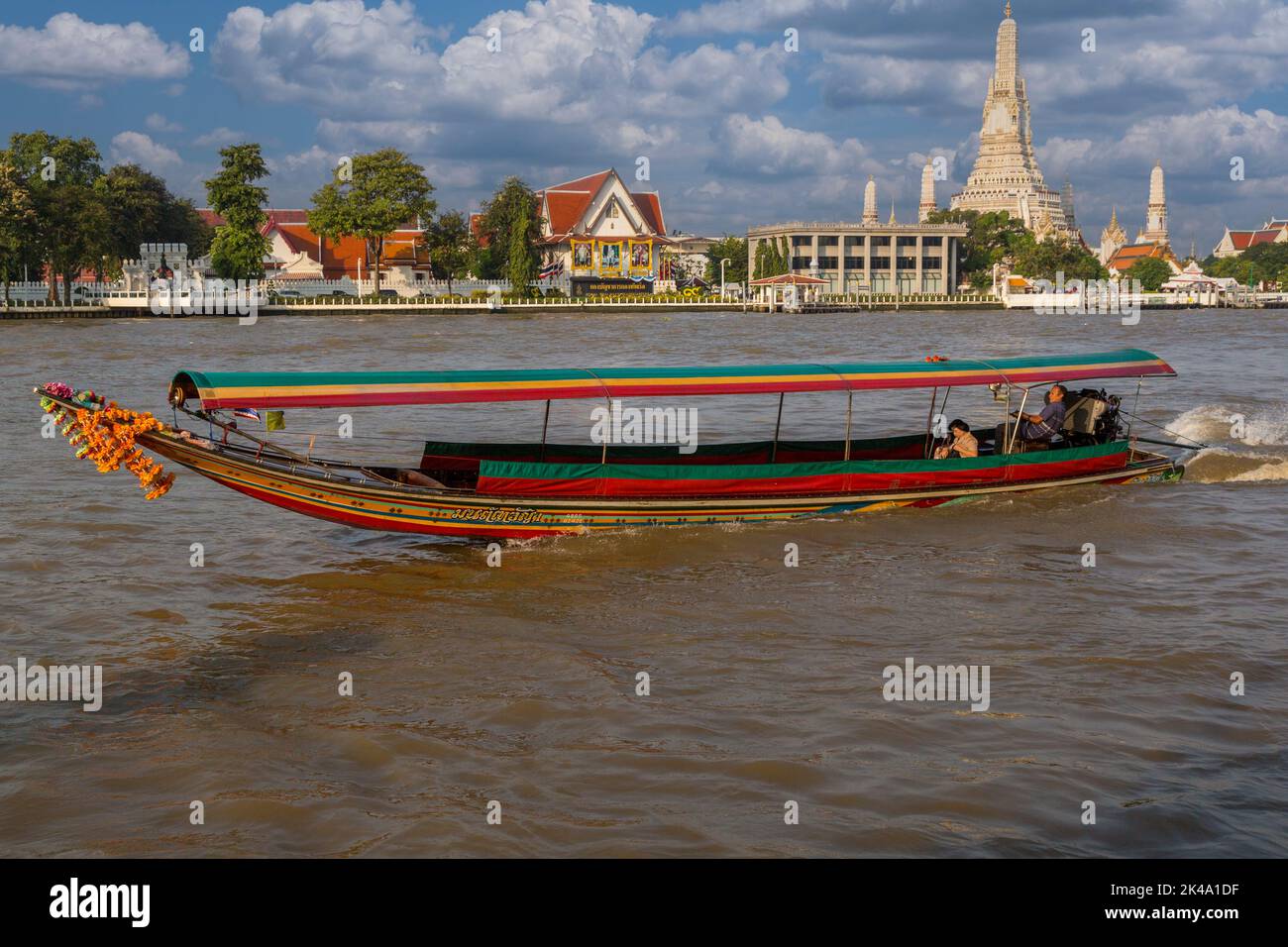 Bangkok, Thailand.  Morning Water Taxi on the Chao Phraya River Takes Passenger to Work.  Wat Arun Temple in the Background. Stock Photo