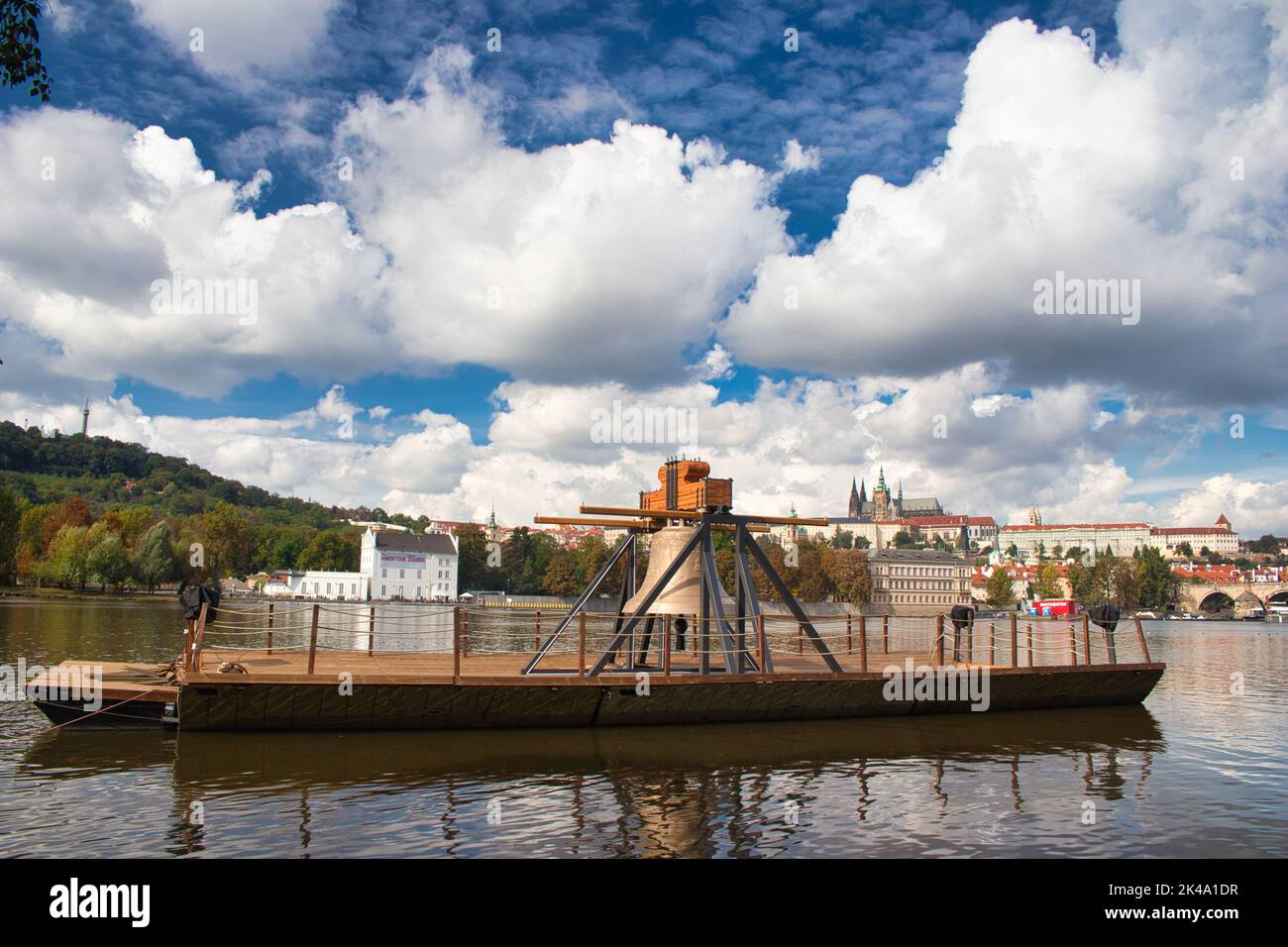The Commemorative bell #9801 on a pontoon in the Vltava river at Smetanovo nábřeží. Prague. Prague Castle and Charles bridge in behind. Stock Photo