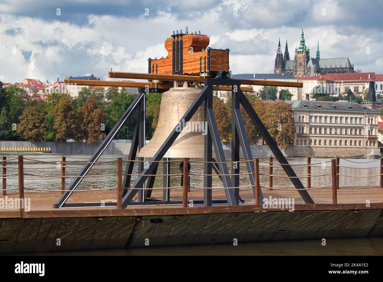 The Commemorative bell #9801 on a pontoon in the Vltava river at Smetanovo nábřeží. Prague. Prague Castle in behind. Stock Photo