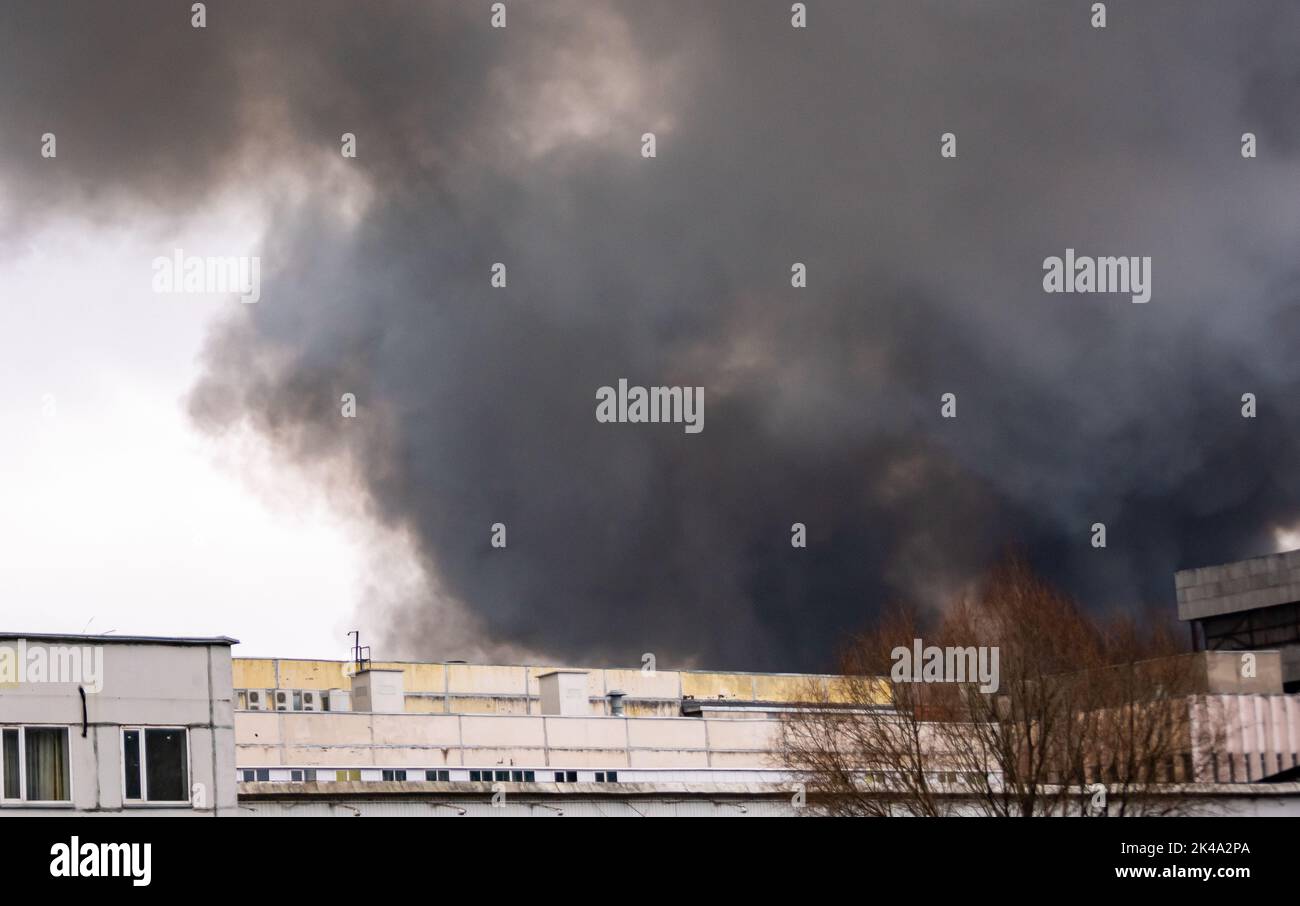 A cloud of black smoke from a fire in a building materials warehouse. Stock Photo