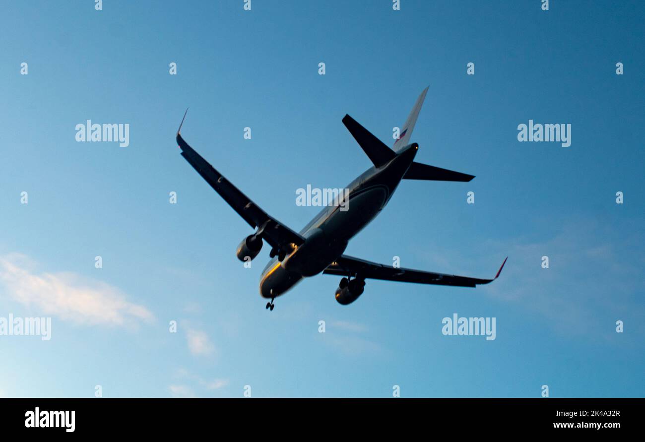 The silhouette of a passenger plane coming in for landing against the backdrop of the sunset sky. Stock Photo