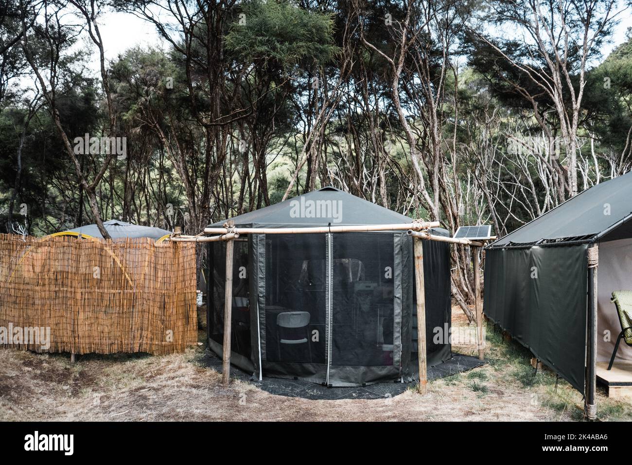 comfortable tents with mosquito nets and wall of reeds on the grass in the silence of the forest among the trees and nature, tarawera lake, new Stock Photo