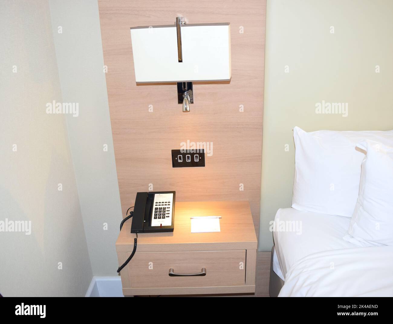 Hotel room with bed and side table in UK Stock Photo Alamy