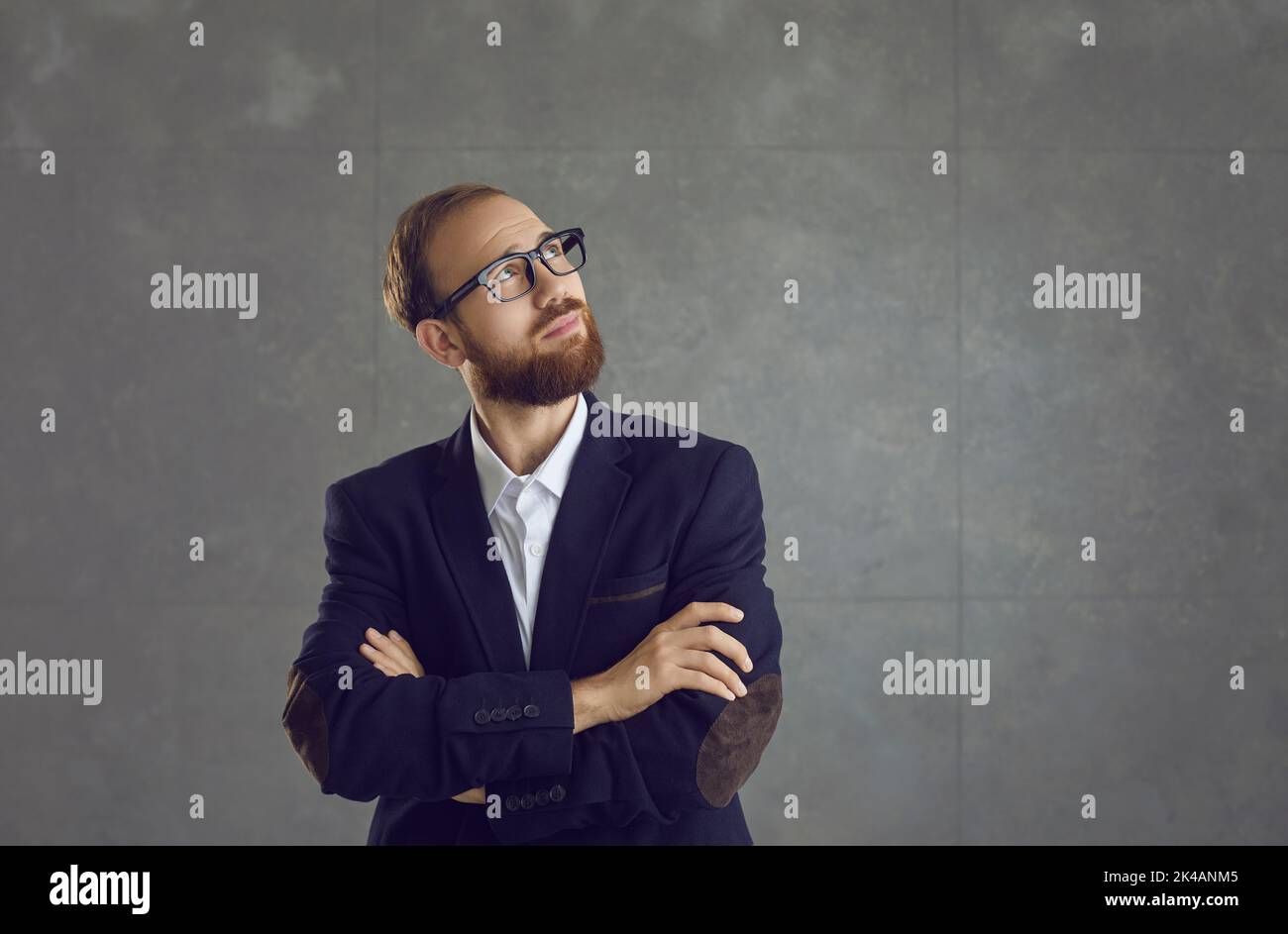 Businessman thinking of an idea and looking away standing on grey copy space background Stock Photo