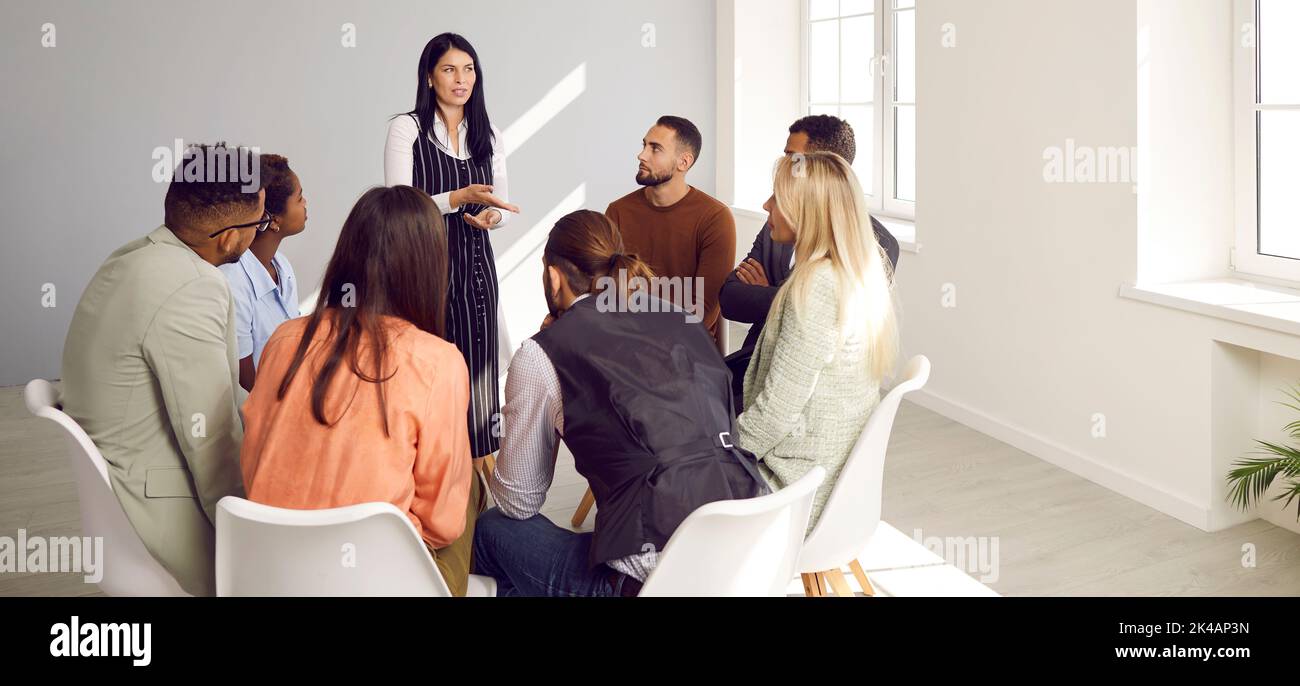 Diverse people sitting in circle take part in group therapy session at psychotherapy meeting. Stock Photo