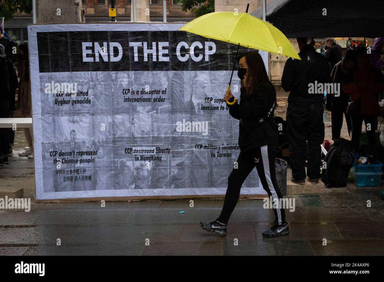 Manchester, UK. 01st Oct, 2022. A protester walks past a banner. Hongkongers take to the streets of the city. People march to raise awareness about the Chinese Communist Party's tyranny which has been targeting politicians, journalists and protesters who rose-up to challenge the Extradition Bill. Credit: Andy Barton/Alamy Live News Stock Photo