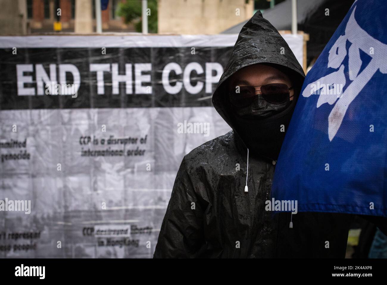 Manchester, UK. 01st Oct, 2022. A protester stands in front of a banner. Hongkongers take to the streets of the city. People march to raise awareness about the Chinese Communist Party's tyranny which has been targeting politicians, journalists and protesters who rose-up to challenge the Extradition Bill. Credit: Andy Barton/Alamy Live News Stock Photo
