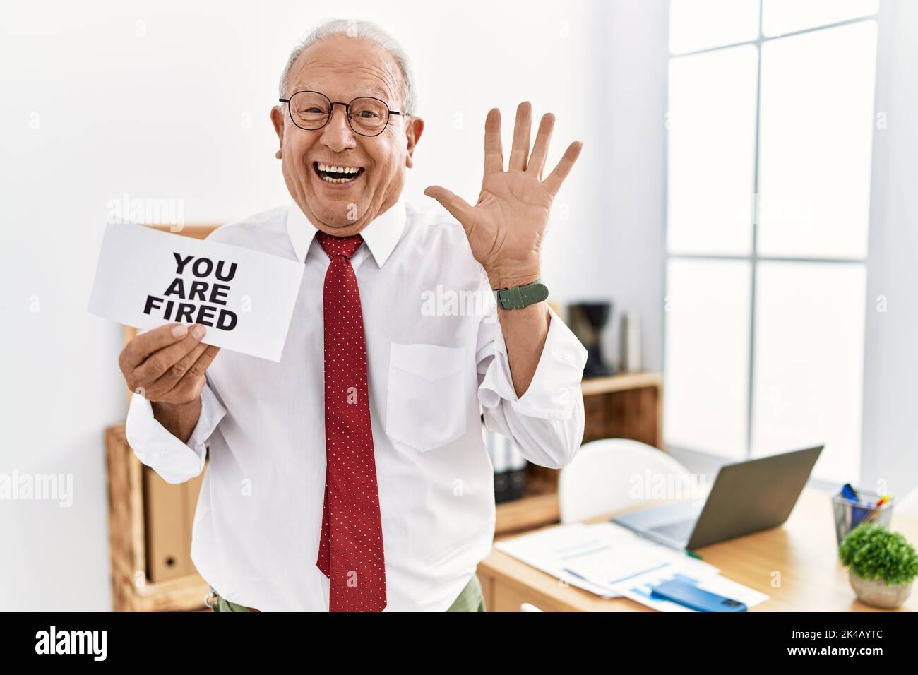 Senior business man holding you are fired banner at the office ...