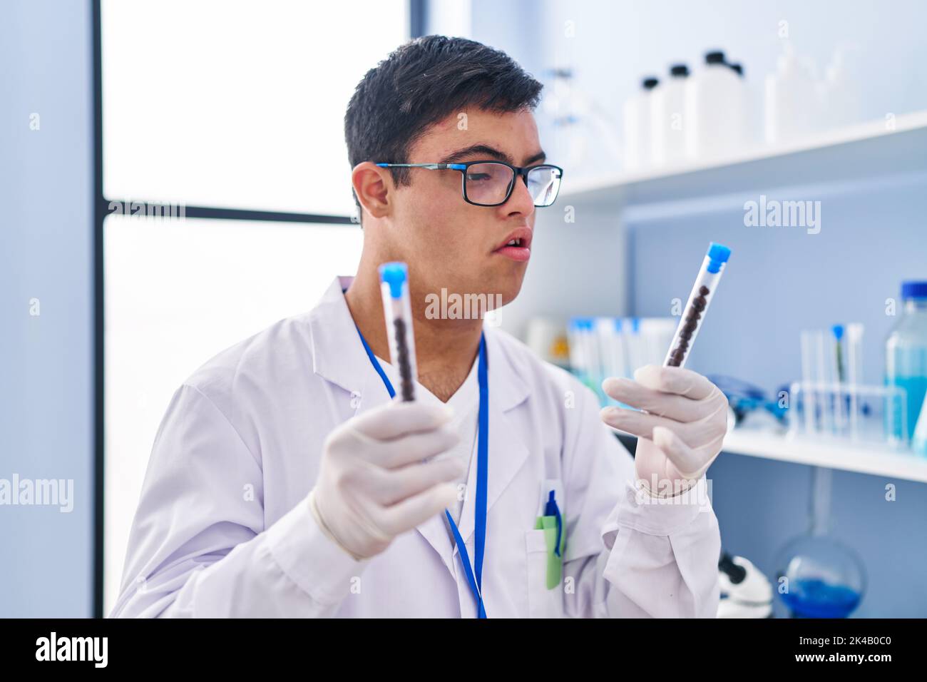 Down syndrome man wearing scientist uniform holding test tubes at ...