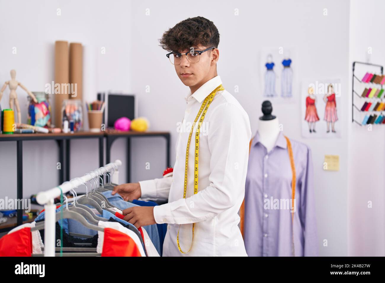 Hispanic Rack Young hispanic teenager tailor holding clothes on rack at tailor shop ...