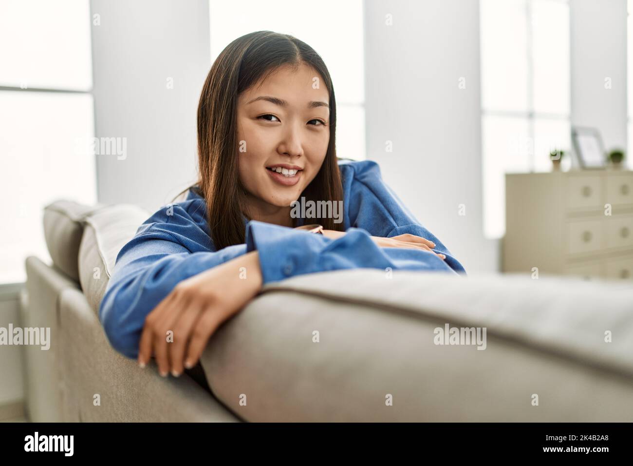 Young chinese girl smiling happy sitting on the sofa at home Stock ...