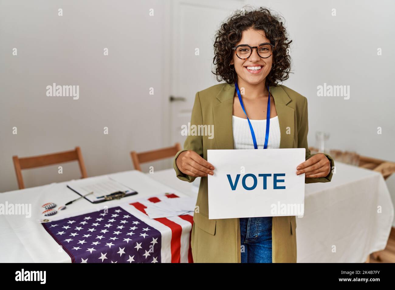 Young hispanic woman smiling confident holding vote banner at electoral college Stock Photo