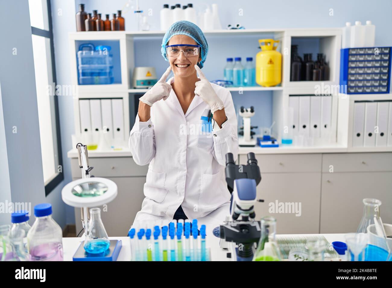 Brunette woman working at scientist laboratory smiling with open mouth ...