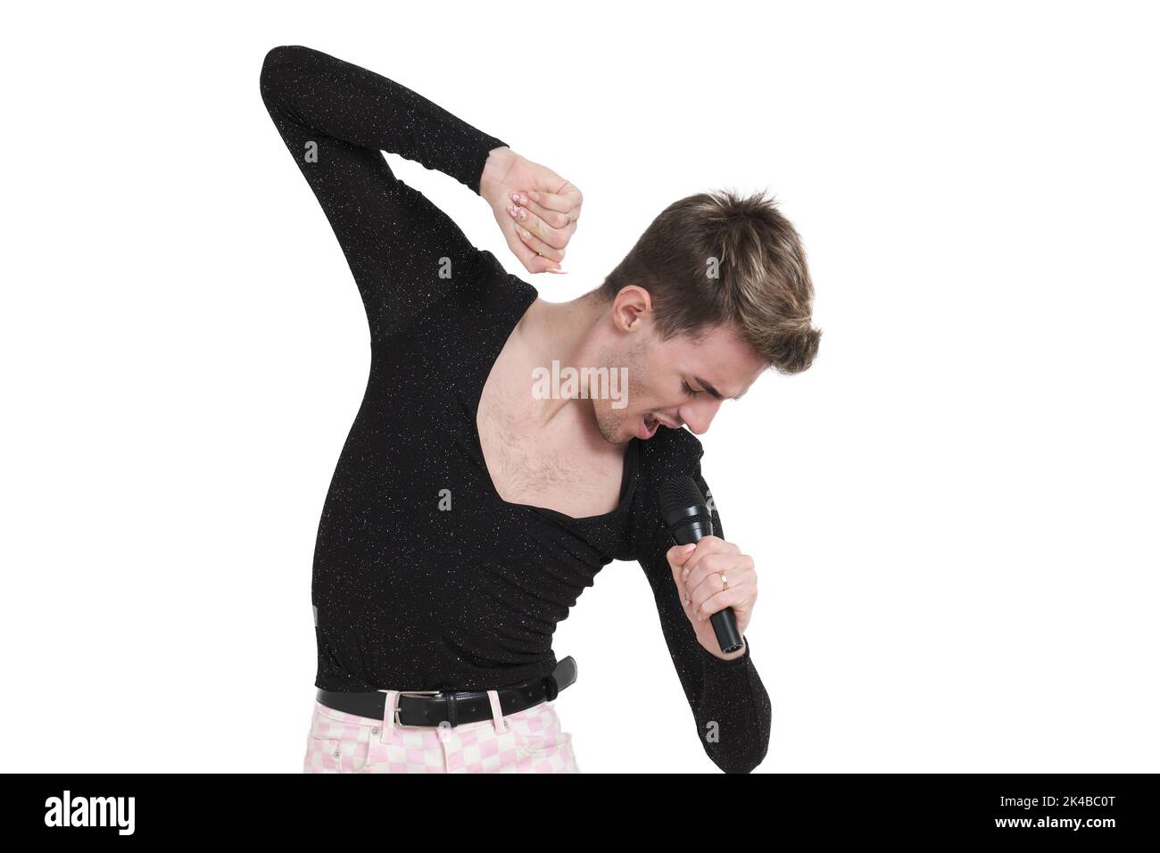 Young caucasian man singing with a microphone, isolated. Stock Photo
