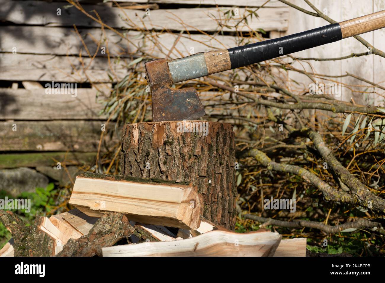 An old retro ax was stuck in a tree stump and cut wood around it on a sunny autumn day in the village. Close up, selective focus Stock Photo