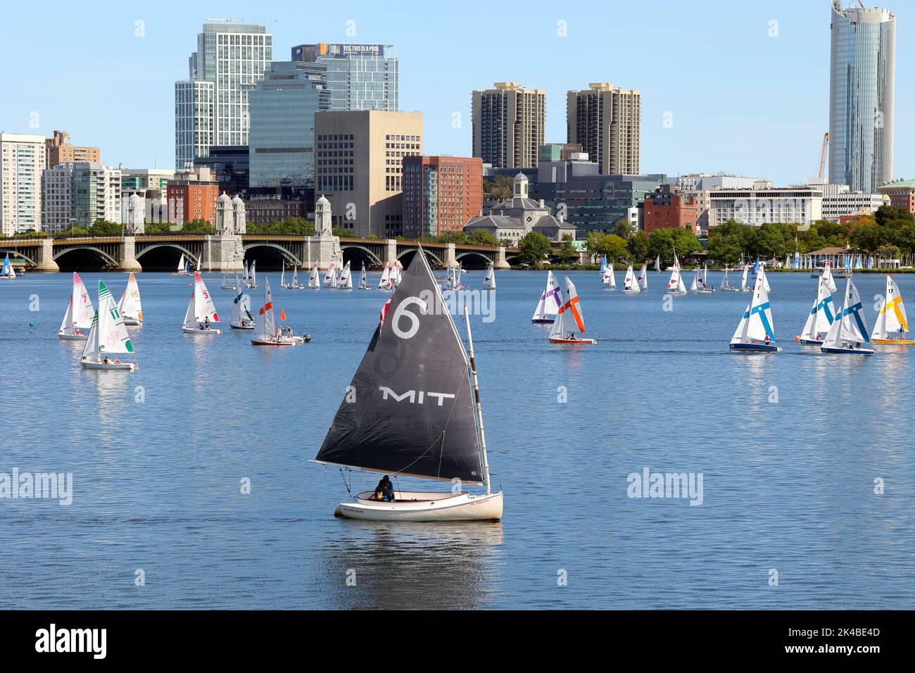 A lone MIT catboat amongst a flotilla of Boston University sailboats on the Charles River with Longfellow Bridge and Boston skyline in the background Stock Photo
