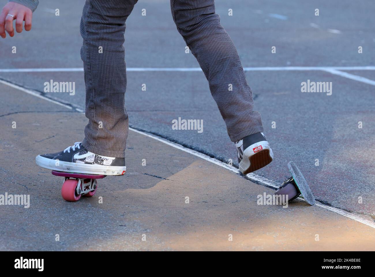 A person with freeline drift skates freeskating on an asphalt playground and falling off a skate Stock Photo