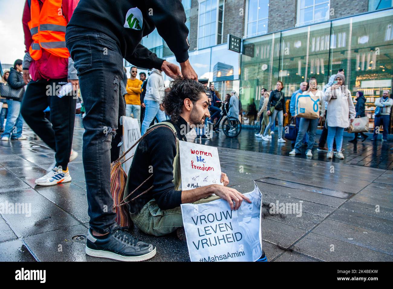 A Man Is Seen Cutting Off The Hair Of A Protester In Front Of A Big a-man-is-seen-cutting-off-the-hair-of-a-protester-in-front-of-a-big