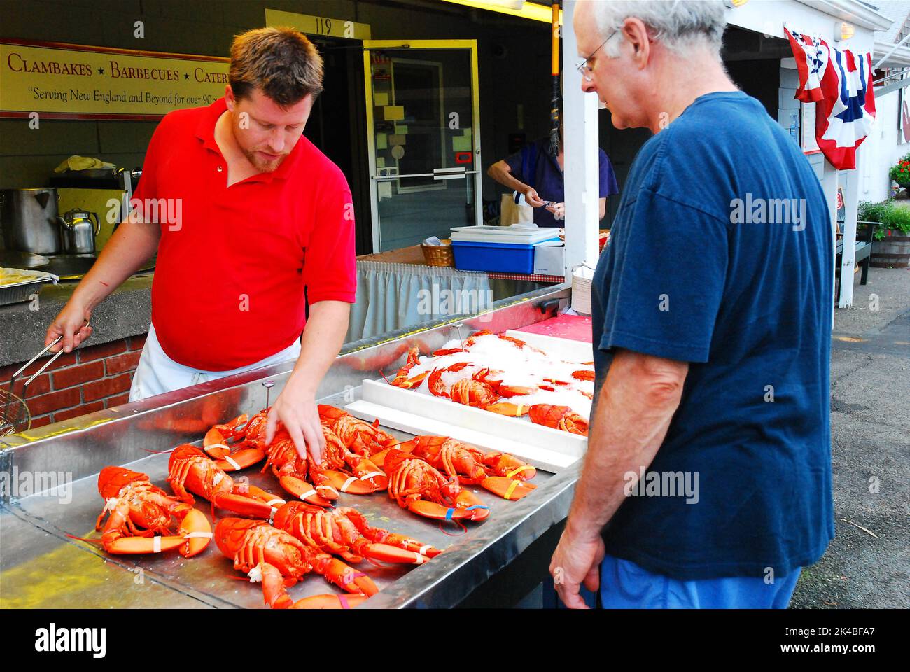 A male worker advises a customer's decision on the selection of lobsters available to choose at a seafood restaurant in New England Stock Photo