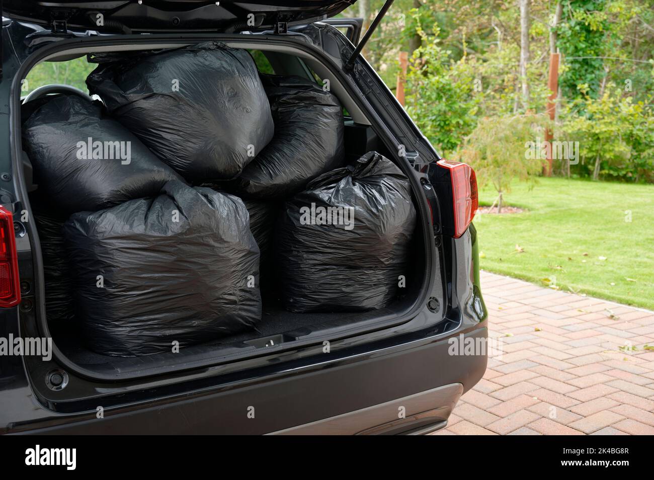 Black plastic bin bags full tied and in car boot with door open for fly