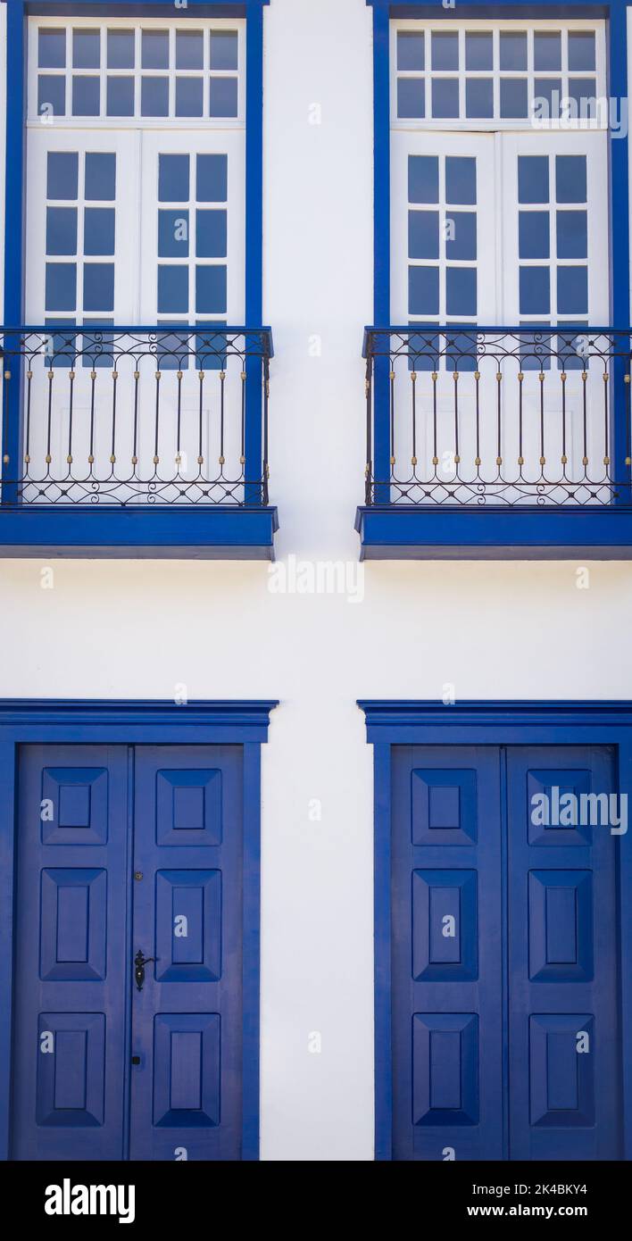 Colonial house façade with windows with white wood panels with cobalt blue trim and cobalt blue wood paneled doors in Sabará, Minas Gerais, Brazil Stock Photo