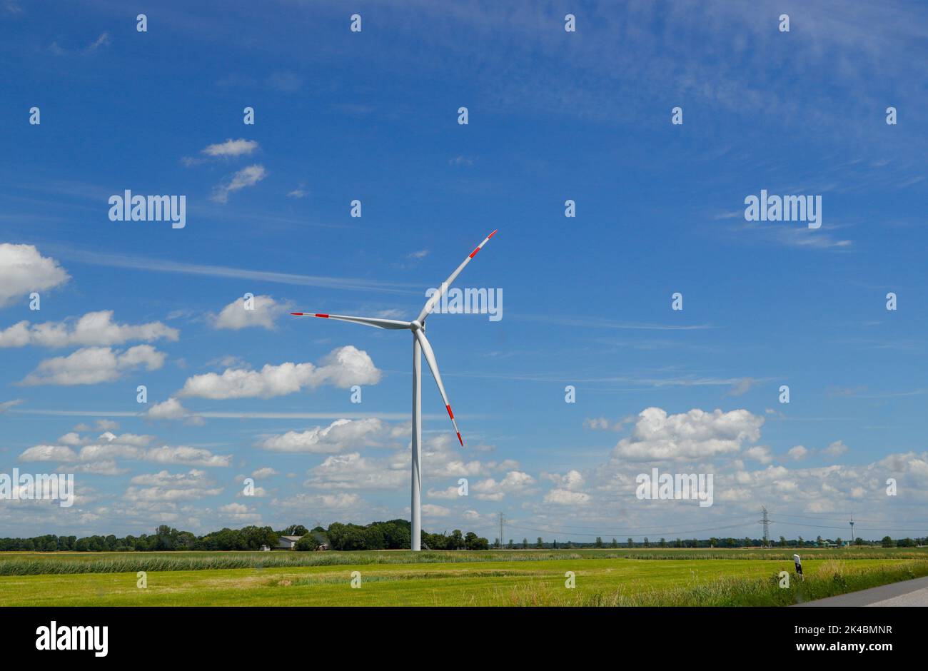 A wind turbine in the field against a blue clouded sky Stock Photo - Alamy