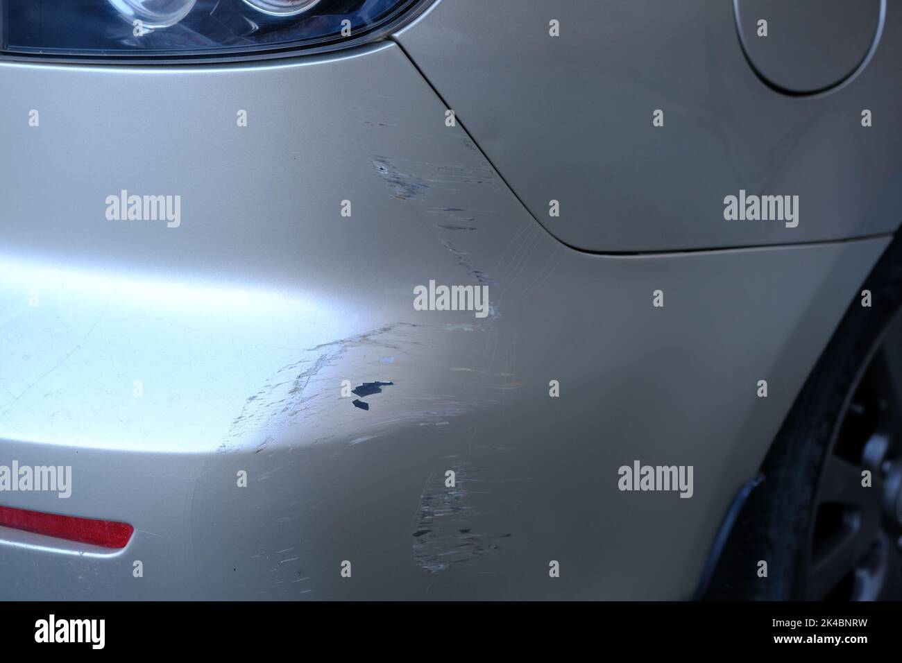 Scratched back bumper on the grey metallic car. Closeup image of