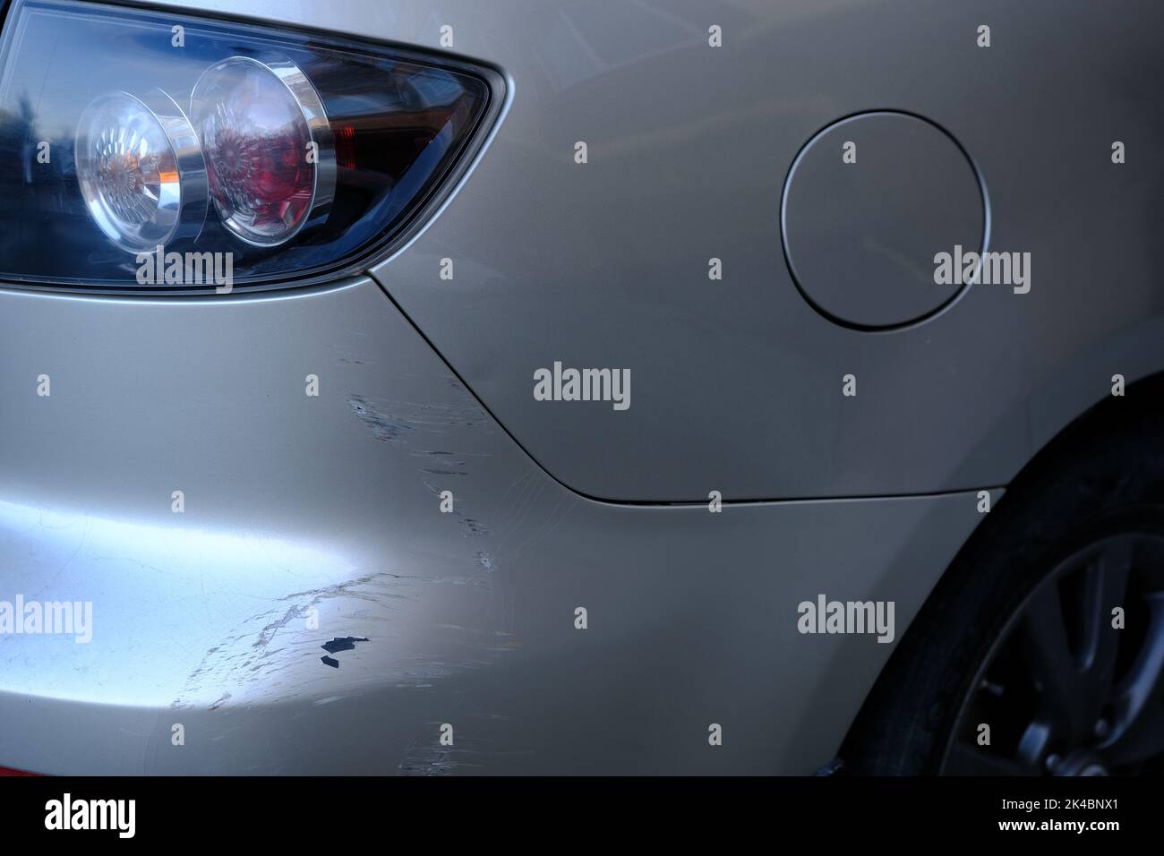 Scratched back bumper on the grey metallic car. Closeup image of damaged back bumper on the car