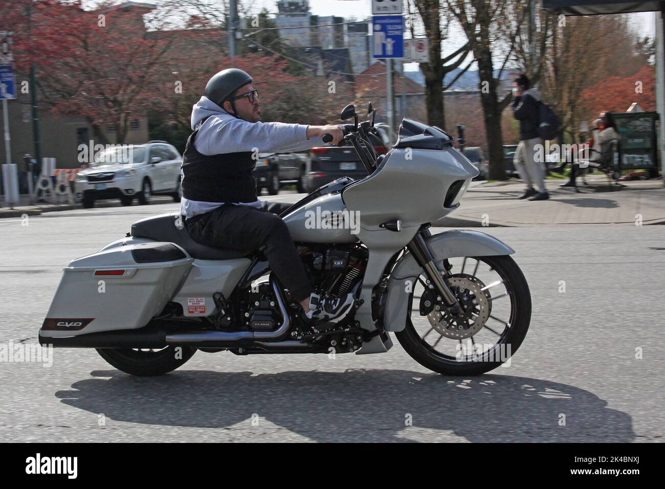 A Man riding a Harley Davidson motorcycle along Commercial Drive in Vancouver, Canada Stock