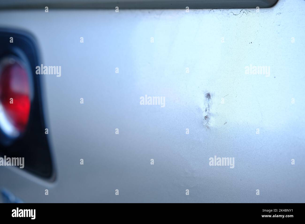 Scratched back bumper on the grey metallic car. Closeup image of