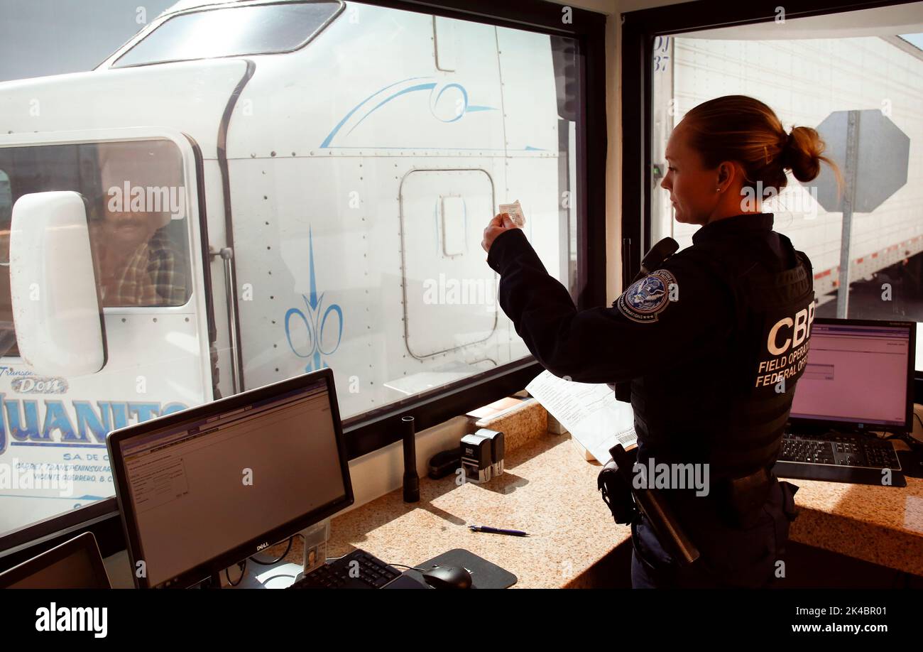 A U.S. Customs and Border Protection officer checks the identification of truck driver as he passes through the U.S. checkpoint of the Cargo Pre-Inspection at the Otay Mesa, Calif.,  port of entry, June 22, 2016. On any given day, several hundred trucks line up on the Mexican side of the border to deliver imports ultimately awaiting the process of screening by customs officers. A growing number of shipping companies are taking advantage of CBP's Cargo Pre-Inspection which allows trusted shippers a faster and more efficient means of delivering products to U.S. retailers. CBP Photo by Glenn Fawc Stock Photo
