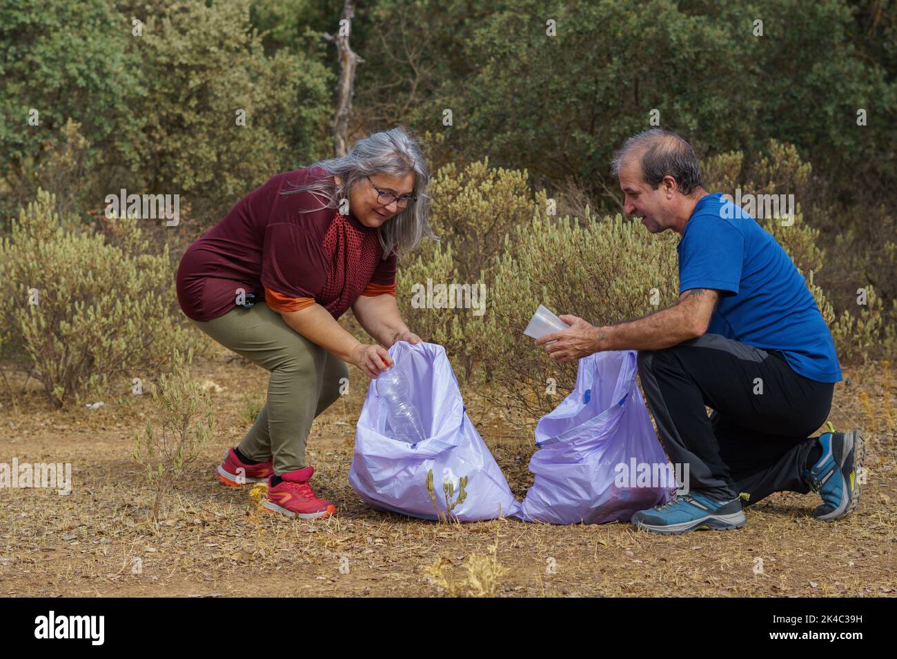 couple of environmentalists collecting garbage from the field in ...