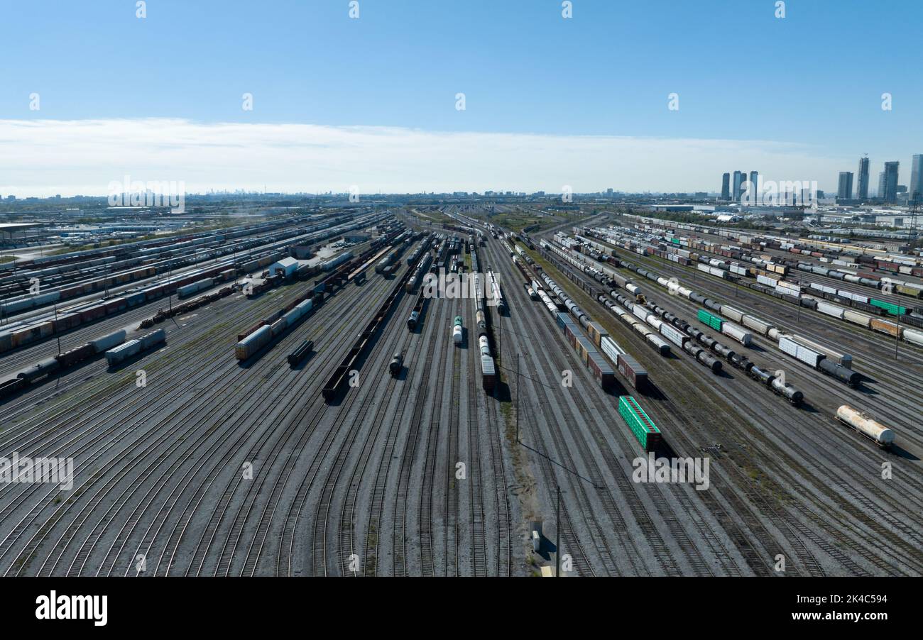 A high aerial view above a vast freight rail yard, seen on a clear, blue sky day. Stock Photo