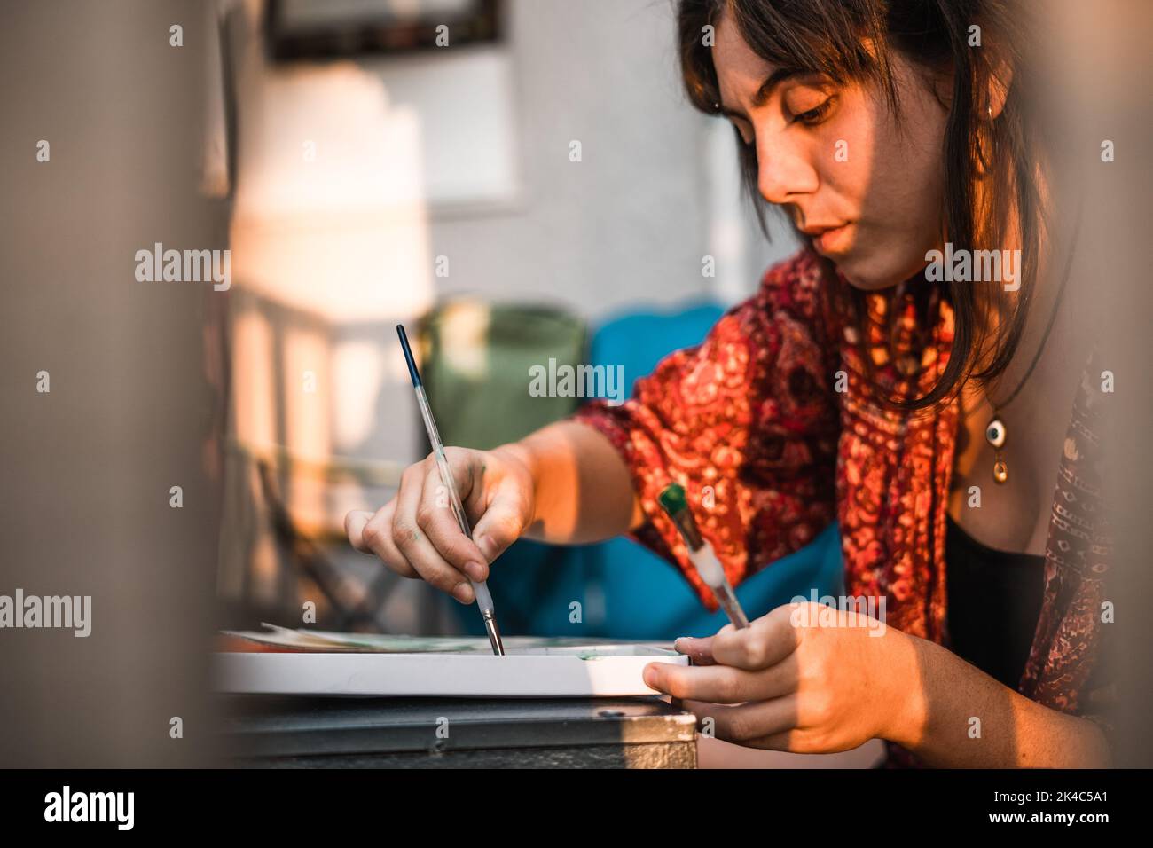 Jover painter in profile painting a canvas behind bars Stock Photo - Alamy