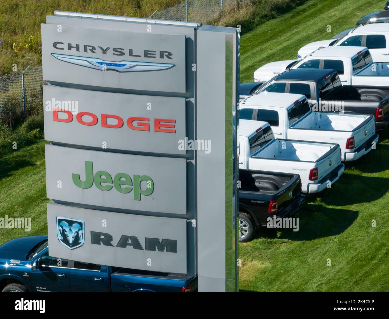 A sign with the Chrysler, Dodge, Jeep and RAM logos on into, out from a large car dealership selling the popular Stellantis brands. Stock Photo